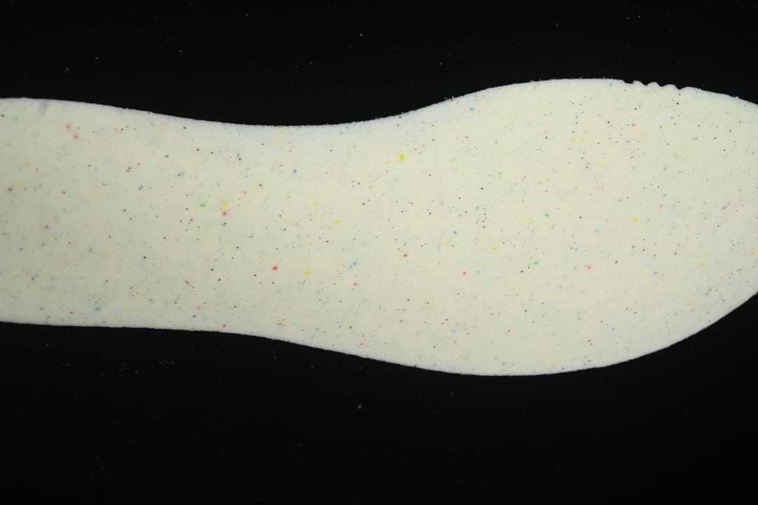 Close-up of a light-colored foam shoe component with multicolor flecks