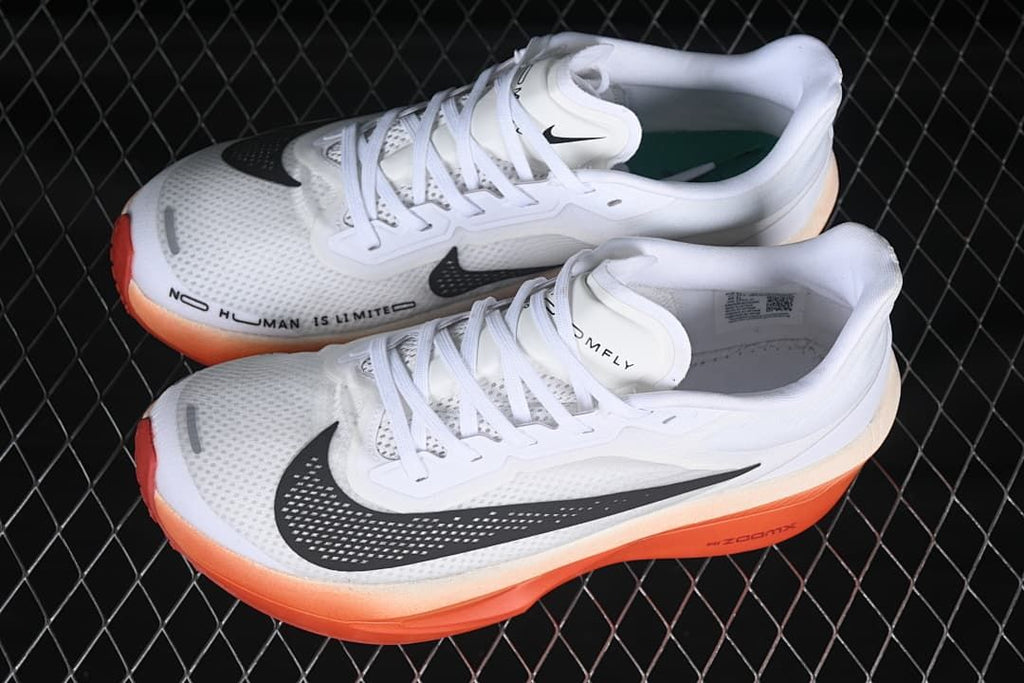 Pair of white running shoes with black swooshes and coral-orange soles