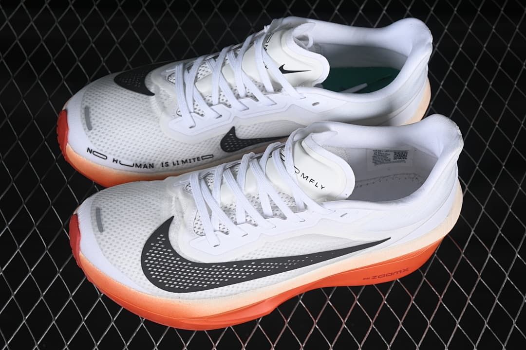 Pair of white running shoes with black swooshes and coral-orange soles