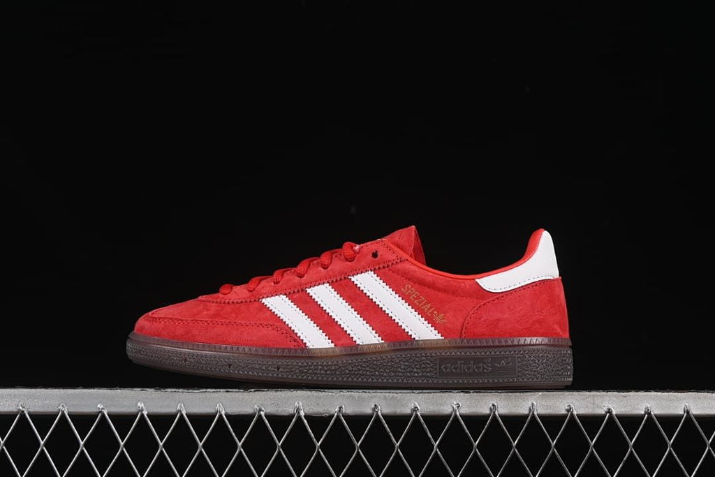 Side view of red adidas Handball Spezial sneakers with white stripes and dark sole