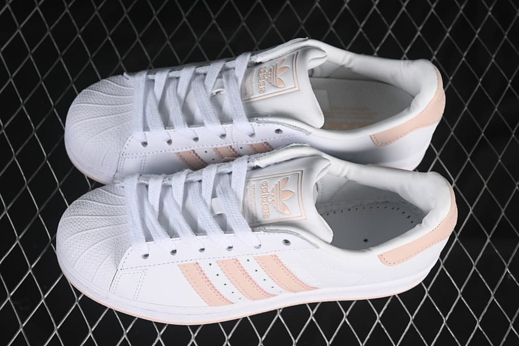 Pair of white and blush-pink Superstar sneakers shown from above.