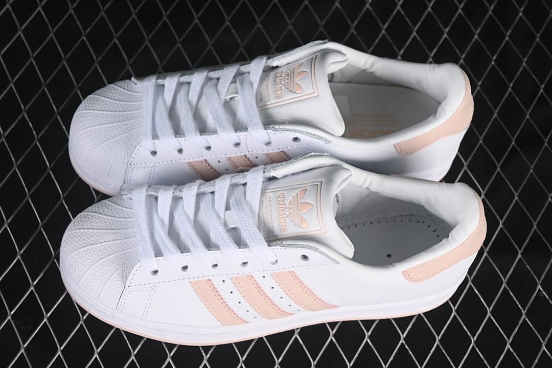 Pair of white and blush-pink Superstar sneakers shown from above.