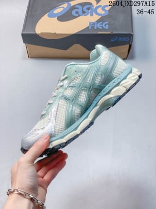 Side profile of the ASICS sneaker showing the light sage upper, pale midsole, and dark outsole details.