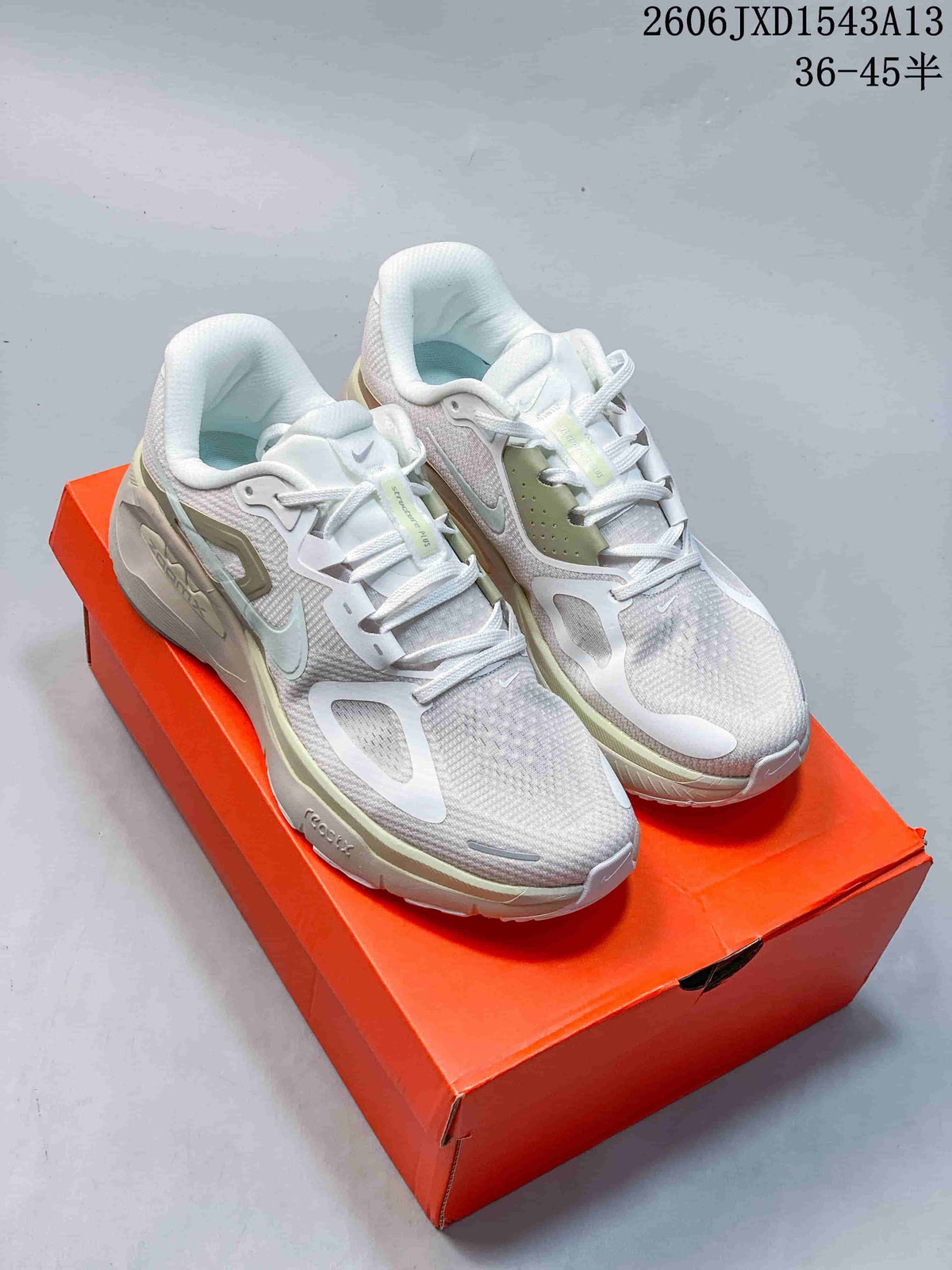 Pair of white and pale green Nike Structure Plus running shoes on an orange shoebox