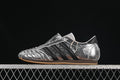 Side view of silver metallic adidas Taekwondo W shoes with black stripes and a forefoot strap.