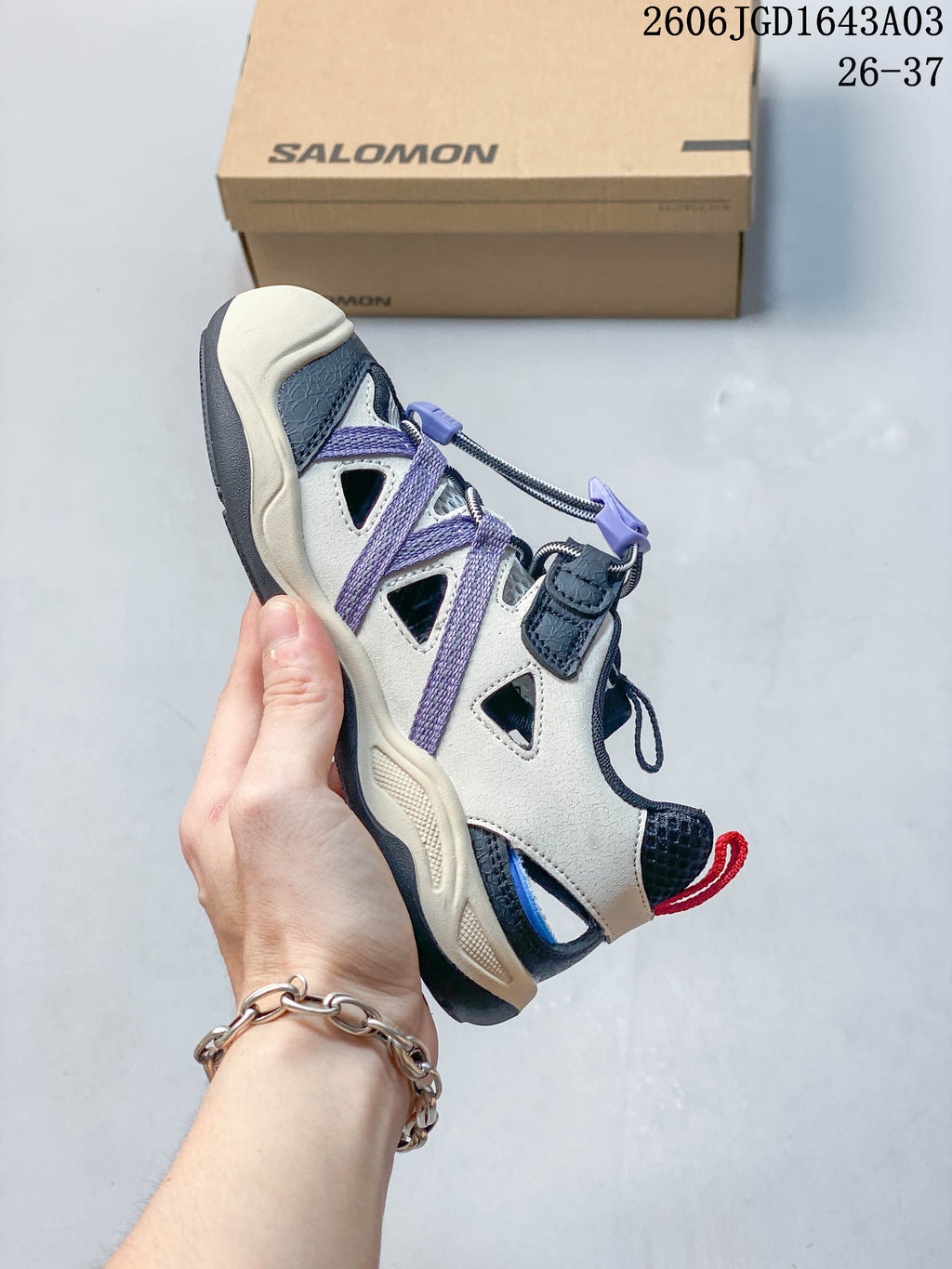 Side view of a cream Salomon kids' sneaker with lavender overlays and a quick-lace closure