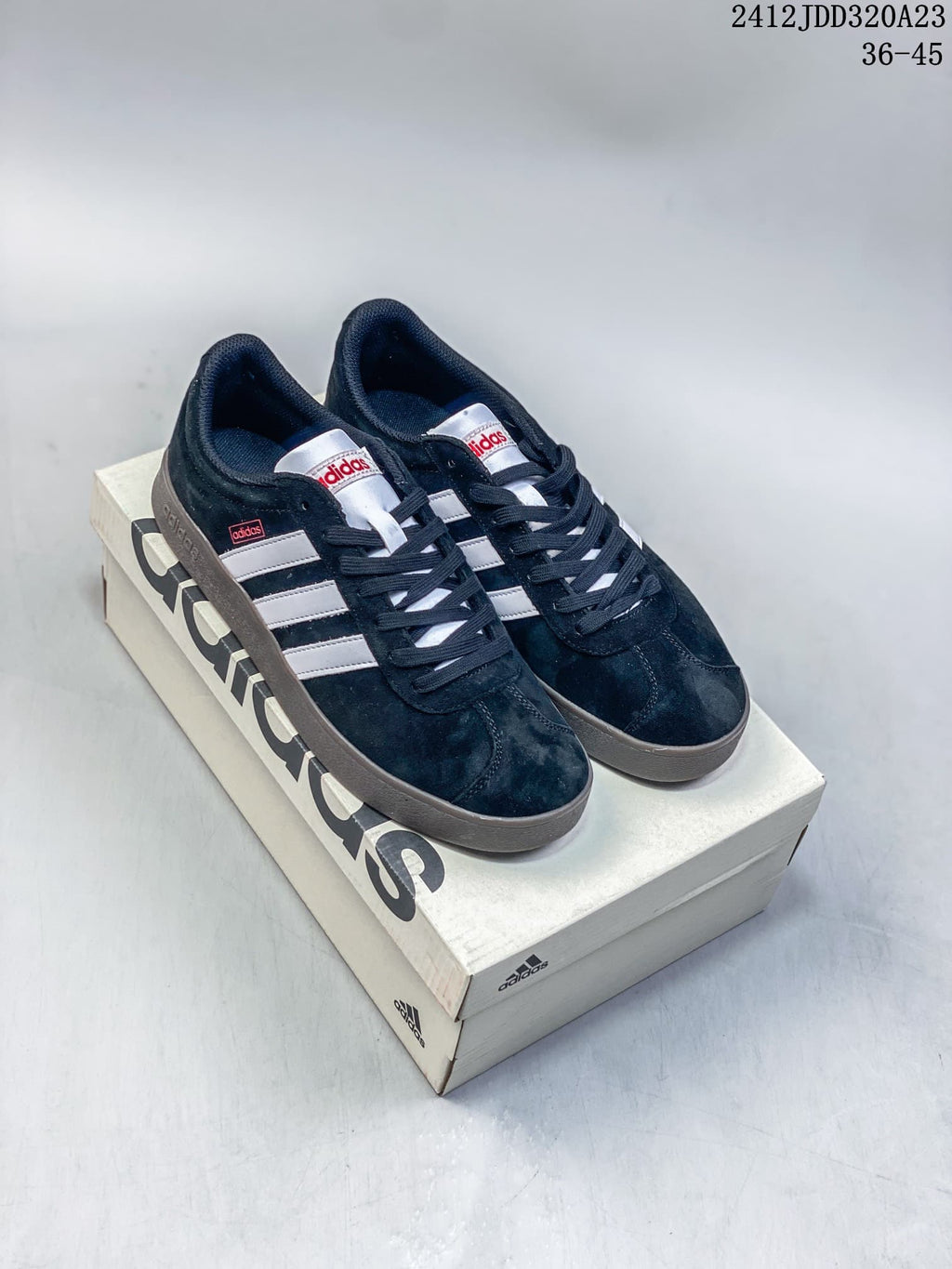 Pair of black Adidas VL Court Classic sneakers with white stripes and gray soles on a shoebox