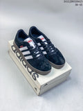 Pair of black Adidas VL Court Classic sneakers with white stripes and gray soles on a shoebox