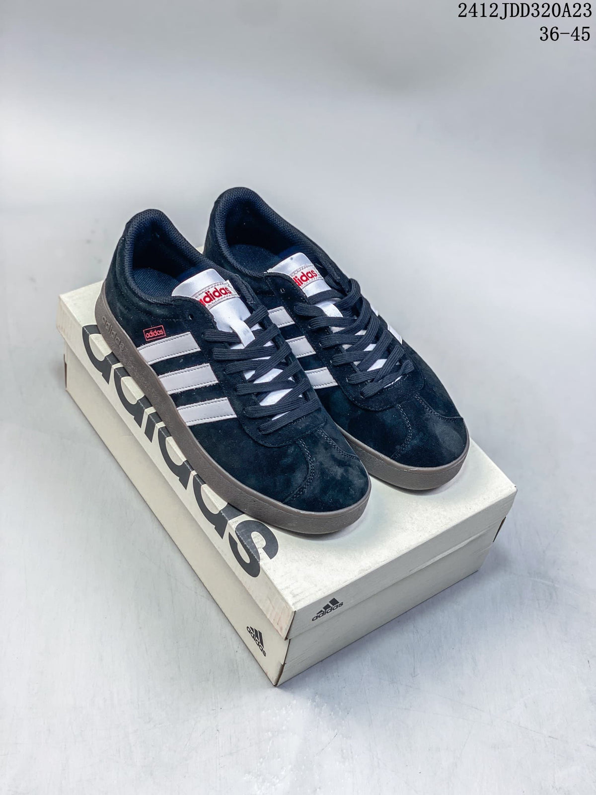 Pair of black Adidas VL Court Classic sneakers with white stripes and gray soles on a shoebox