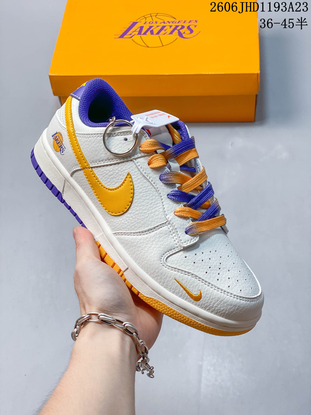 Angled side view of the white sneaker with gold Swoosh, Lakers detail, purple accents, and multicolor laces