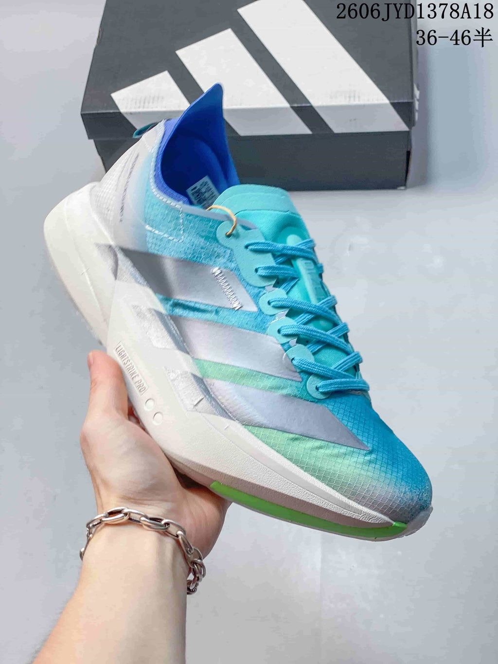 Angled side view highlighting the shoe's turquoise upper, silver stripes, and white midsole