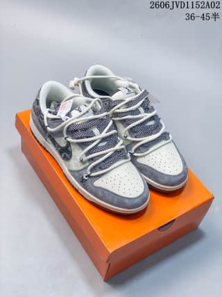Pair of white and gray low-top sneakers displayed on an orange shoe box, showing the patterned overlays, white laces, and perforated toe boxes.
