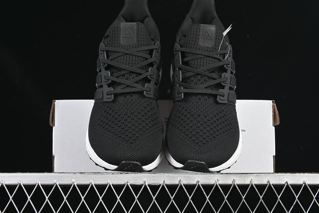 Front view of the pair of black knit running shoes on a shoebox.
