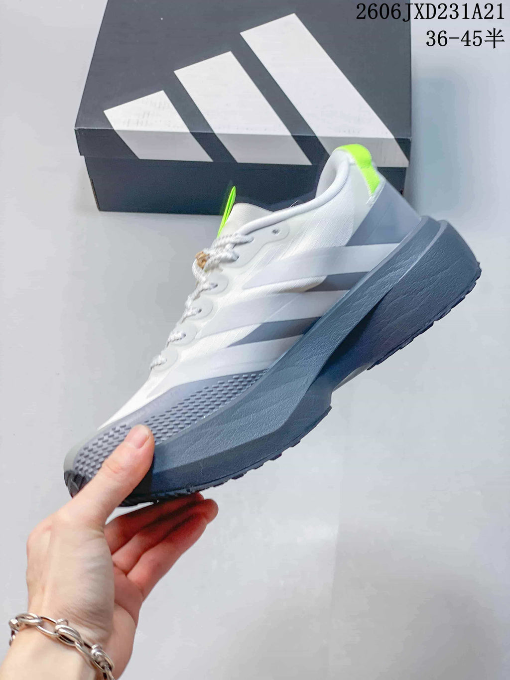 Side view of a white and grey low-top running shoe with three stripes and lime heel detail.