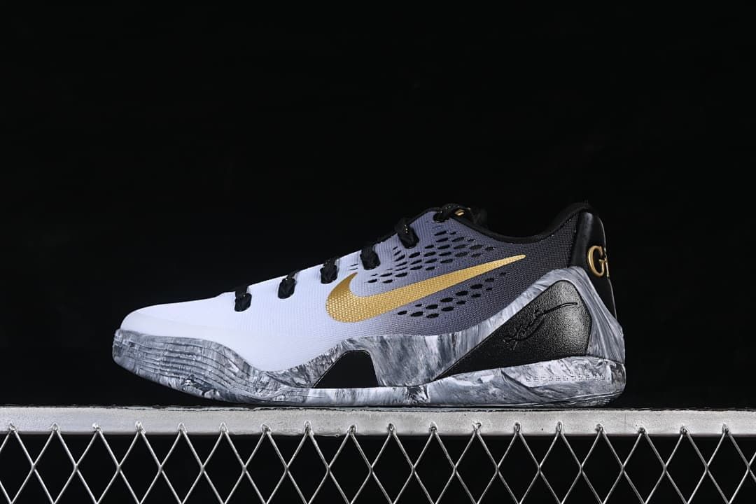Side view of a white, gray, black, and gold low-top Kobe basketball shoe