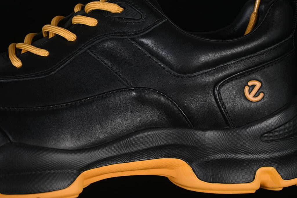 Close-up of the black side panels, amber logo, and contrasting outsole