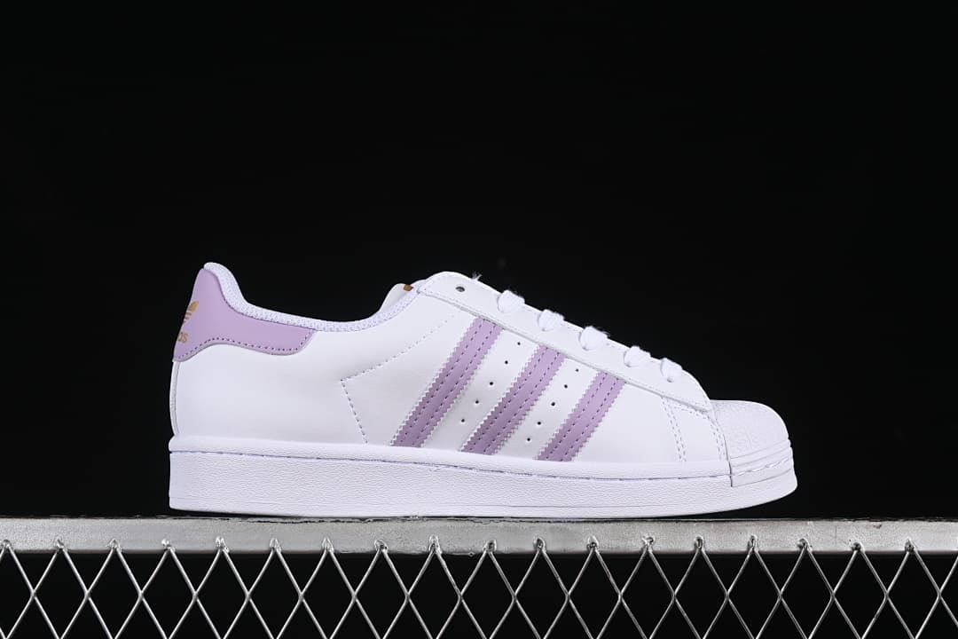 Side profile of a white Superstar sneaker with lavender stripes