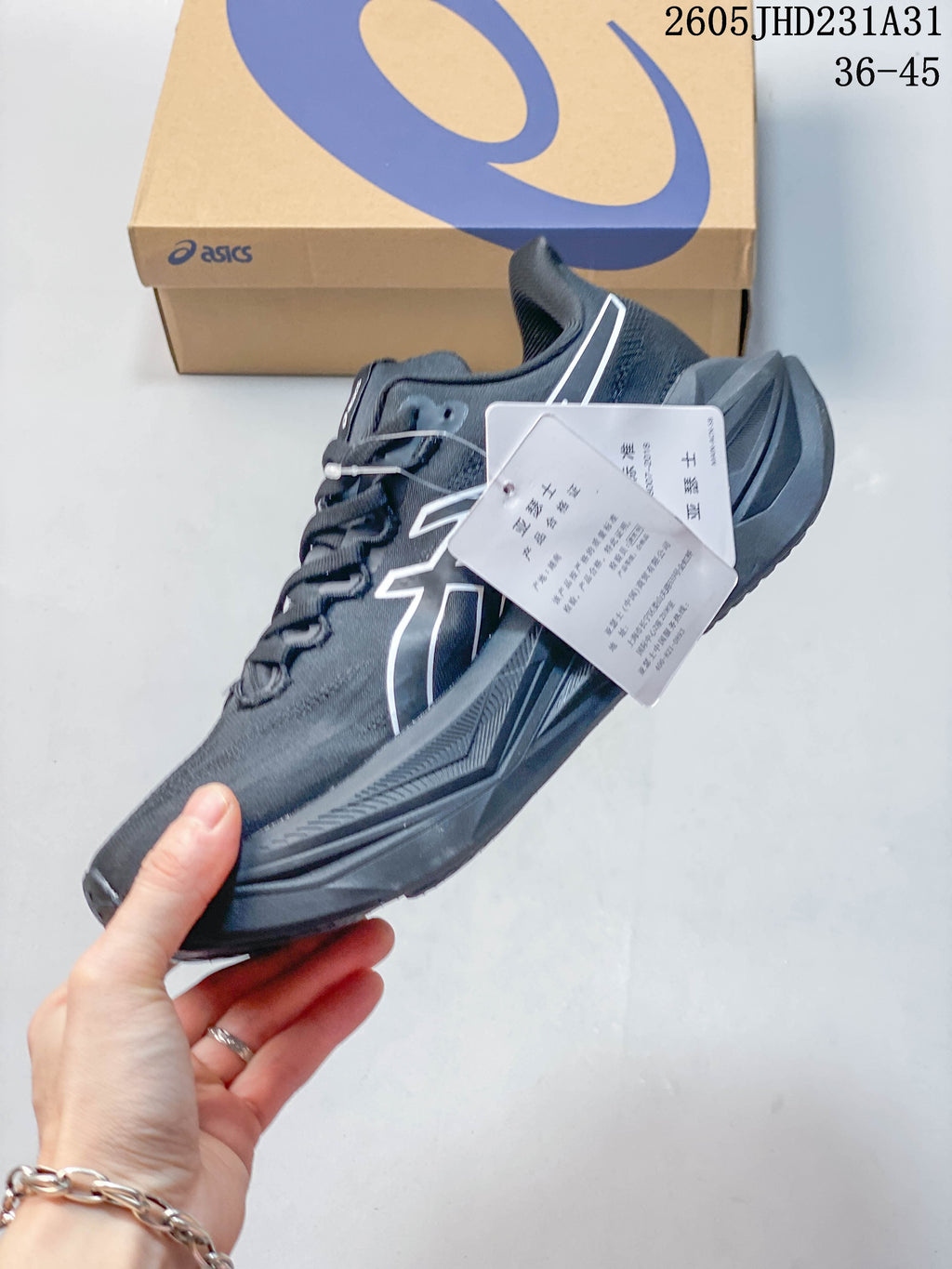 Side view of a dark gray ASICS running shoe with product tags