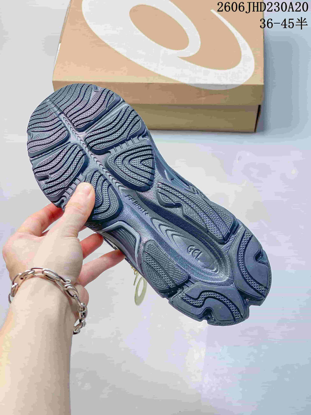 Close-up of the patterned outsole on a navy and silver ASICS sneaker