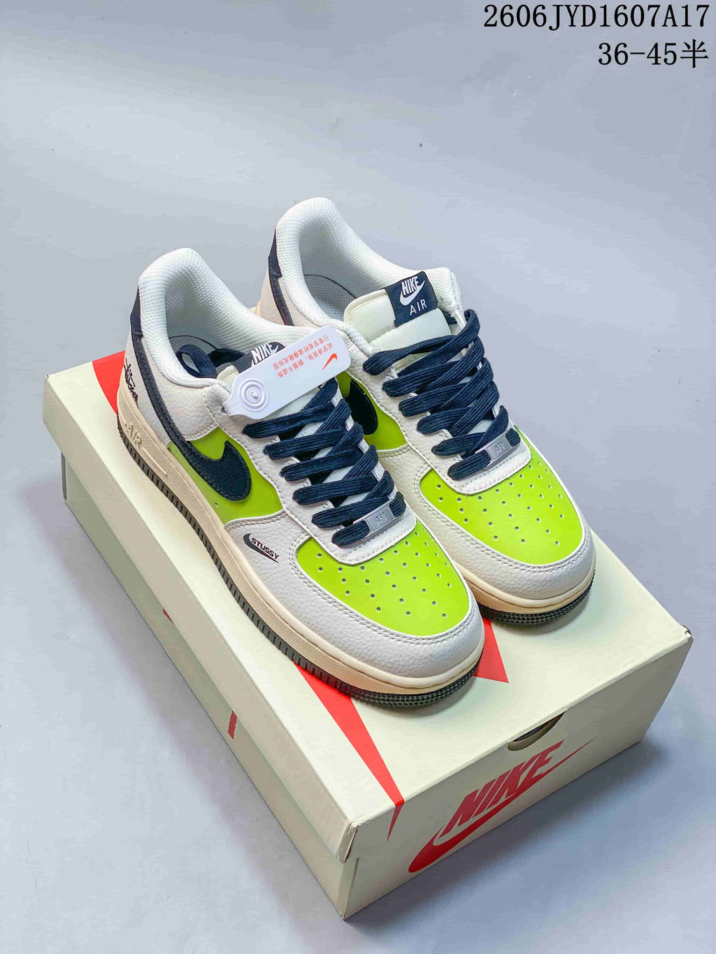 Pair of low-top sneakers with white and bright lime panels, navy laces and Swooshes, displayed on a shoebox.
