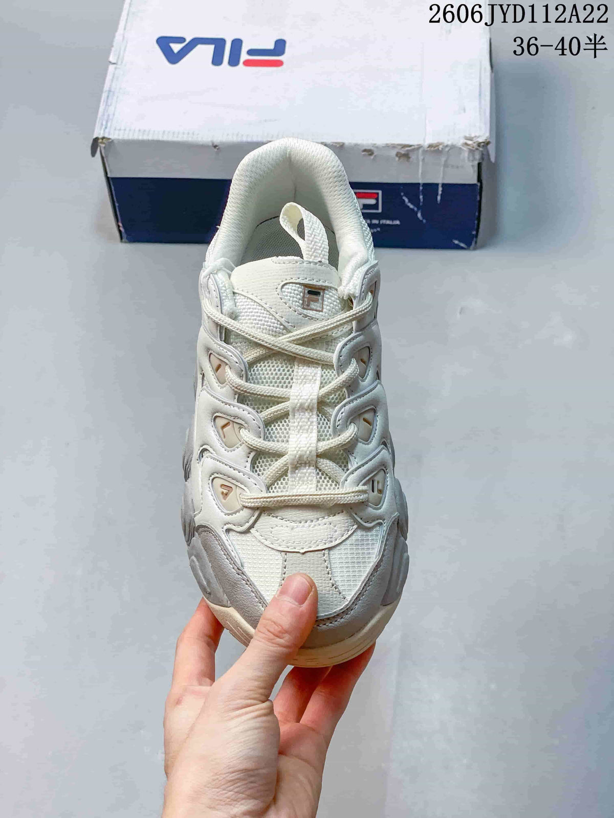 Front view of a white and grey FILA sneaker with lace-up closure