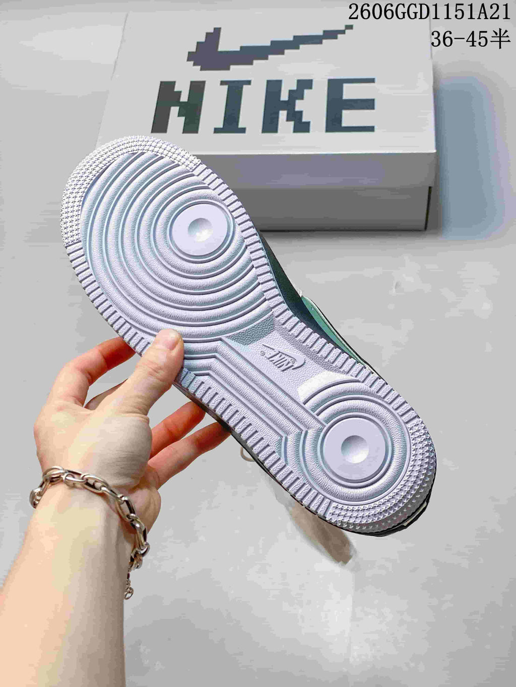 Outsole view of the sneakers beside a shoebox