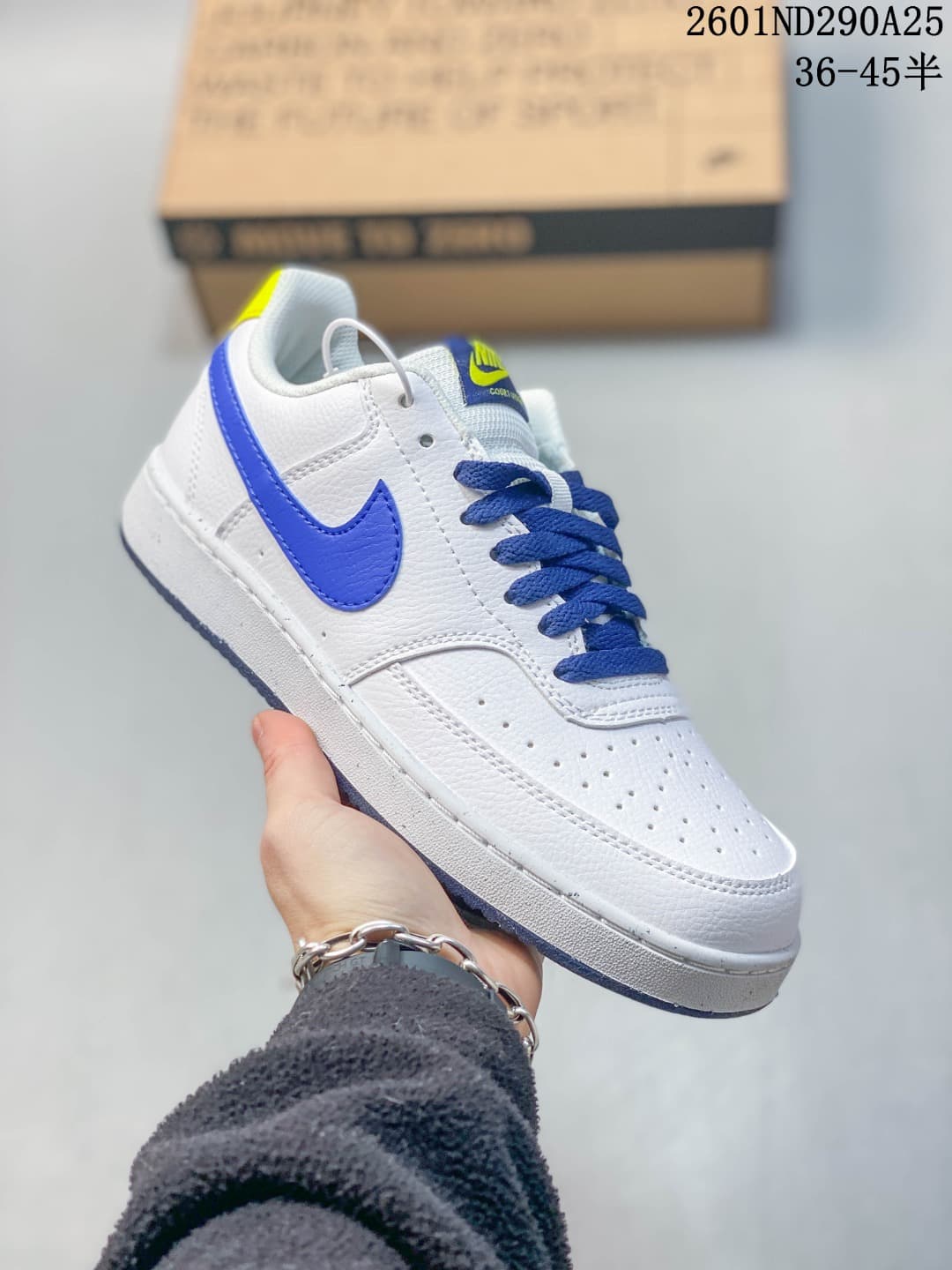 Angled side view of the white sneaker with blue accents and a yellow heel detail.