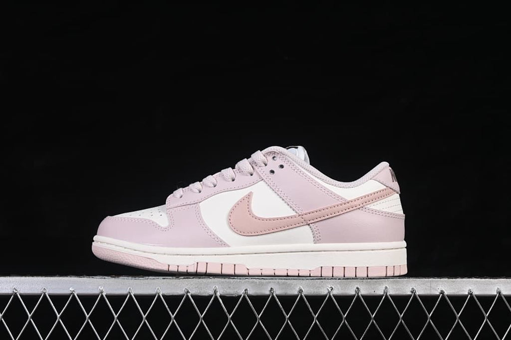 Side view of pale pink and white Nike Dunk Low sneakers