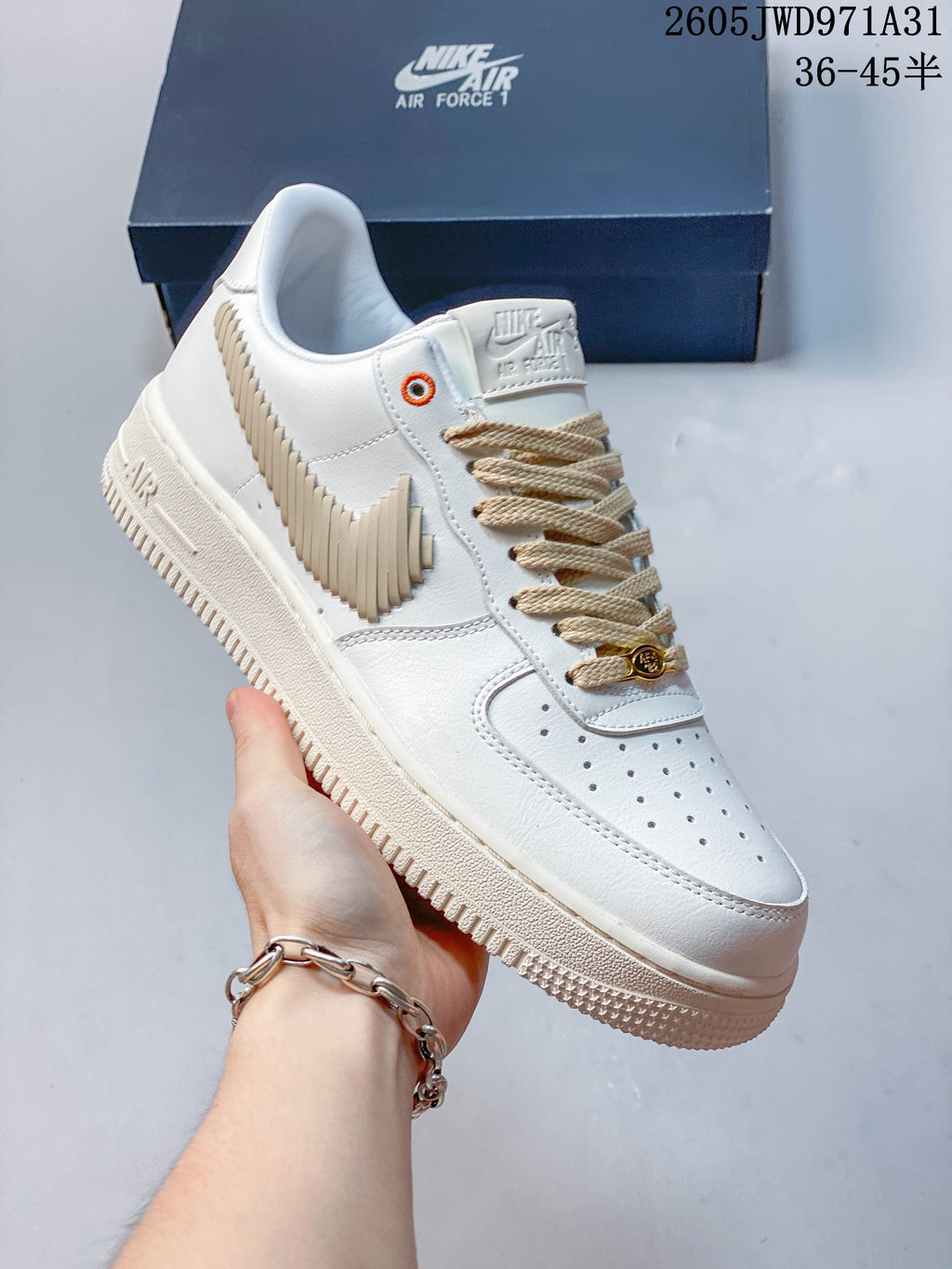 Angled view of a white low-top sneaker with a layered beige side detail, beige laces and light-colored sole.