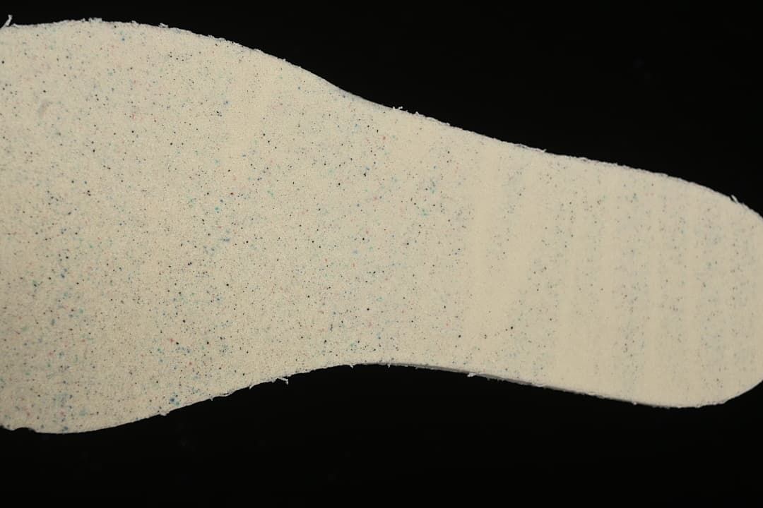 Close-up of a light-colored shoe component with a speckled surface.