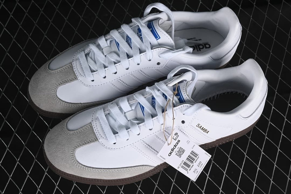 Pair of white adidas Samba OG sneakers with light gray toe panels and gum soles