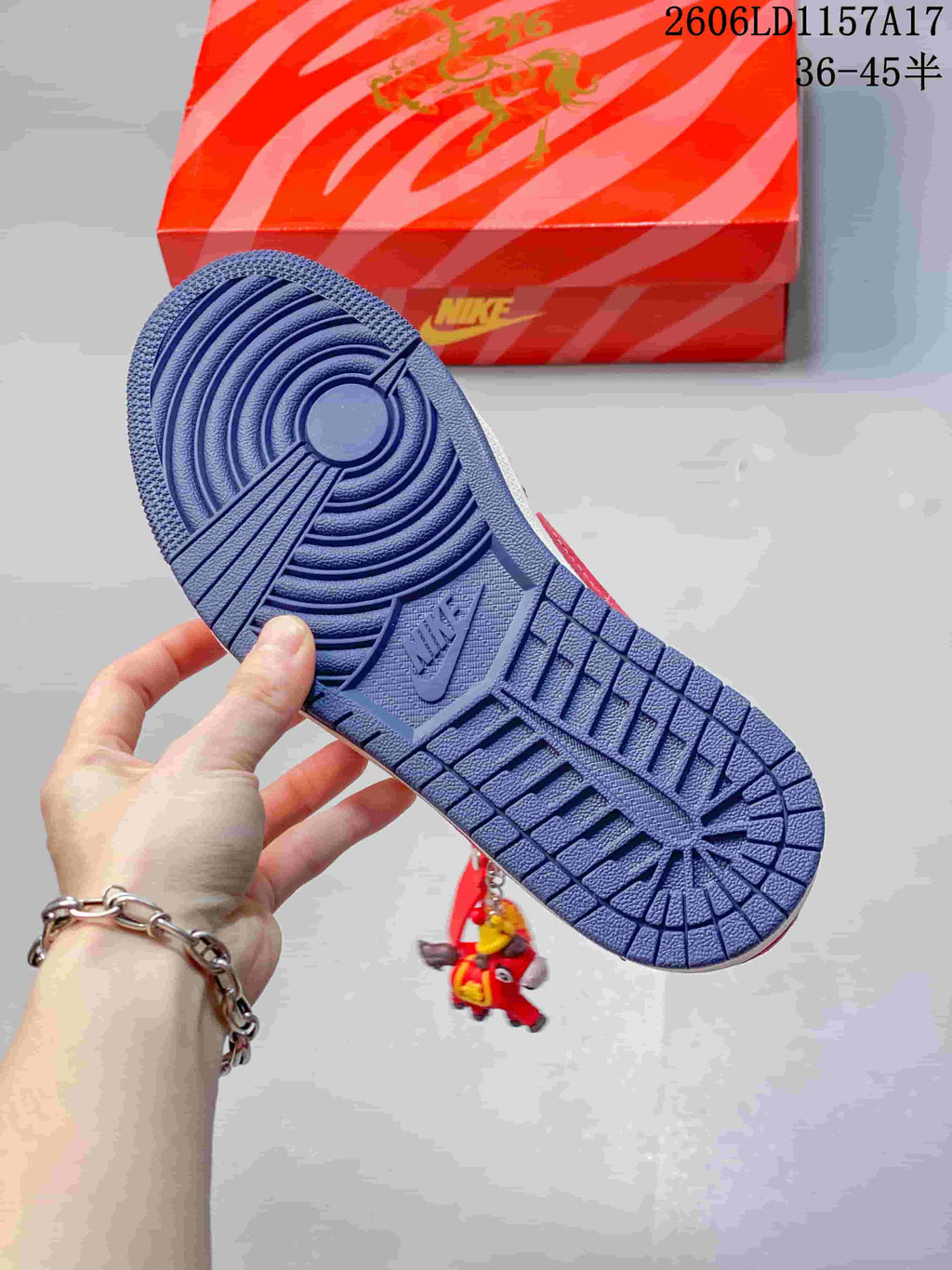 Navy outsole shown beside the red shoe box, with a decorative charm visible.