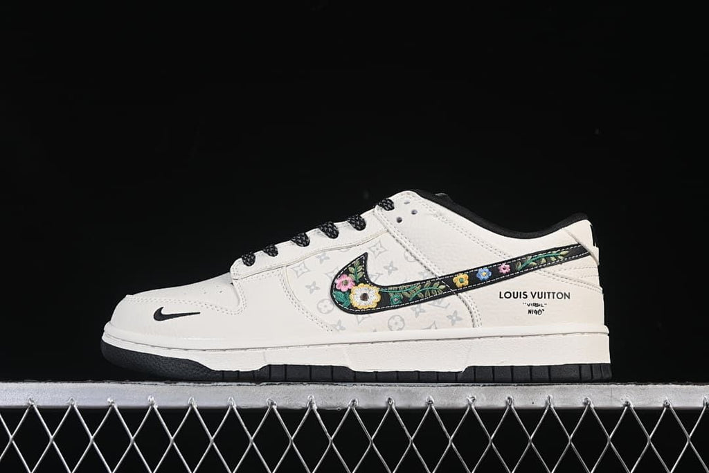 Side view of a cream low-top sneaker with black laces and outsole, pale patterned panels, and a floral embroidered side Swoosh.