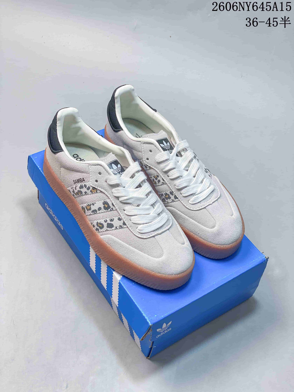 Off-white Adidas Sambae sneakers with patterned side stripes and a raised gum-look sole on a blue shoe box.