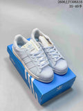 White and pale blue Adidas Superstar II sneakers shown on a blue shoebox
