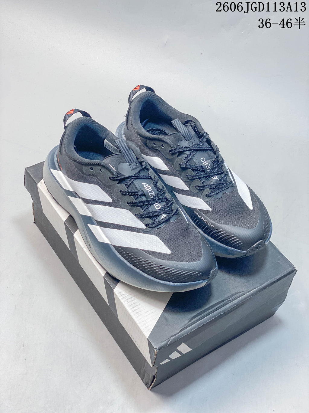 Pair of charcoal gray Adidas Adizero Evo SL ATR shoes with white side stripes, shown on a shoebox.