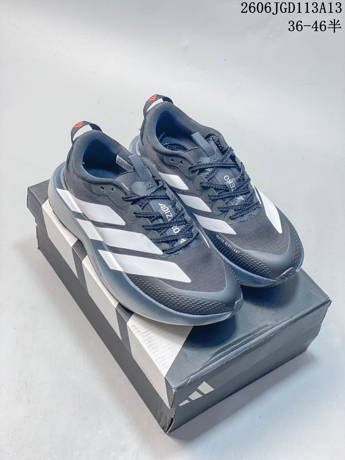 Pair of charcoal gray Adidas Adizero Evo SL ATR shoes with white side stripes, shown on a shoebox.