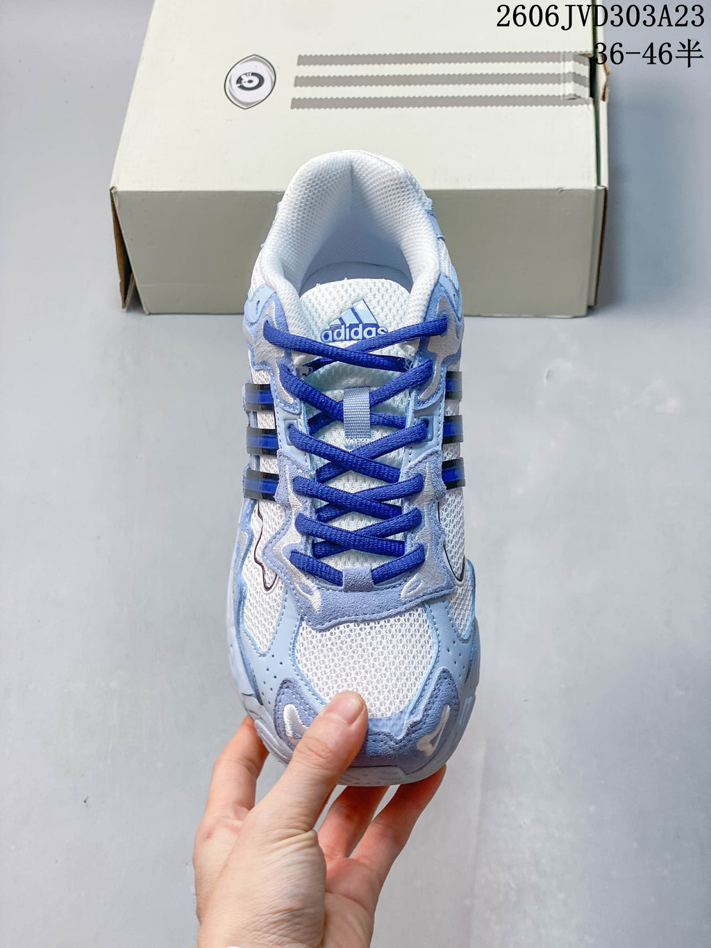 Top view of the sneaker with white mesh, blue laces, and layered overlays