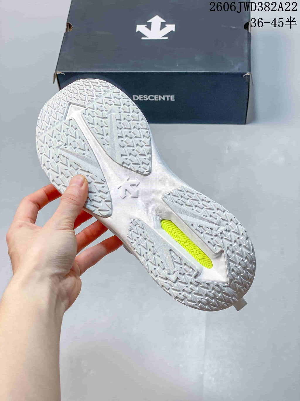 Underside of the white DESCENTE running shoe showing its patterned outsole.