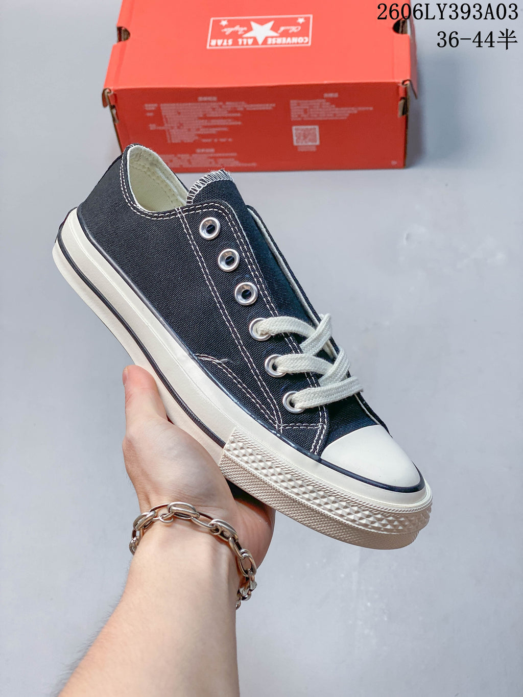Black low-top lace-up sneaker with white stitching and an off-white sole
