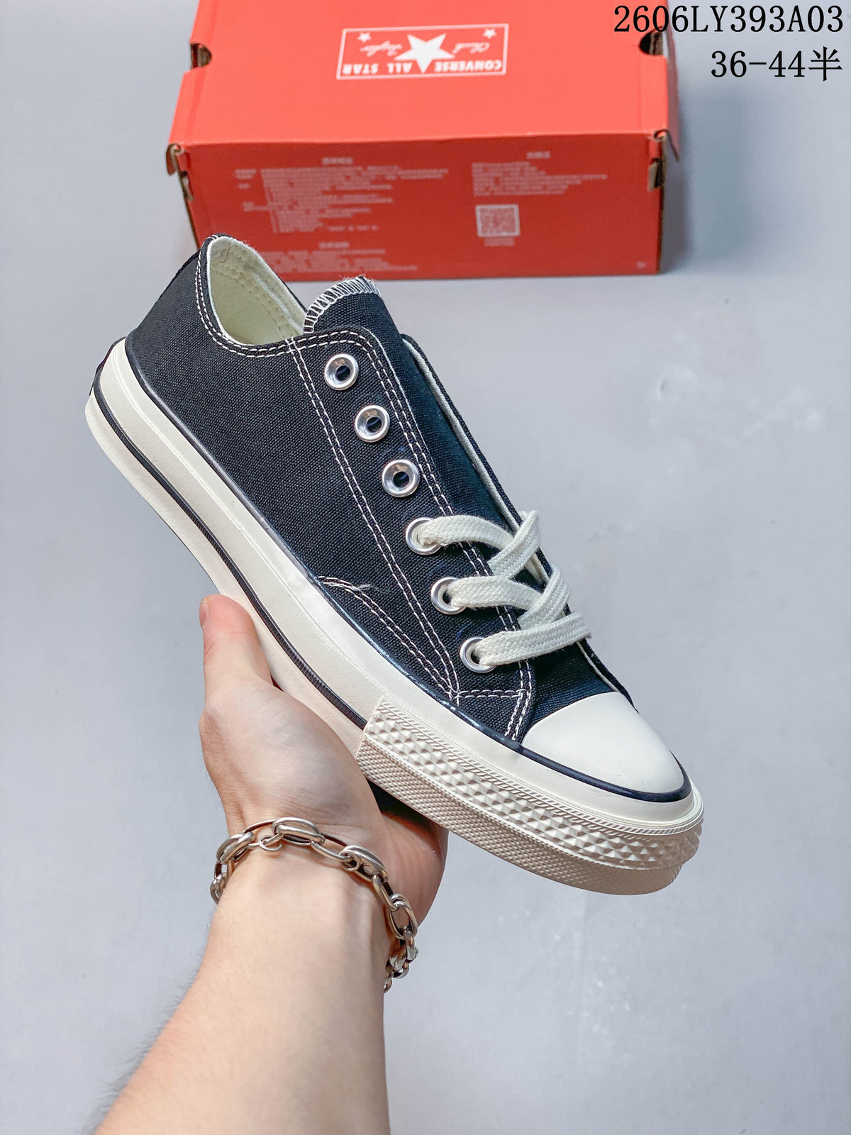 Black low-top lace-up sneaker with white stitching and an off-white sole