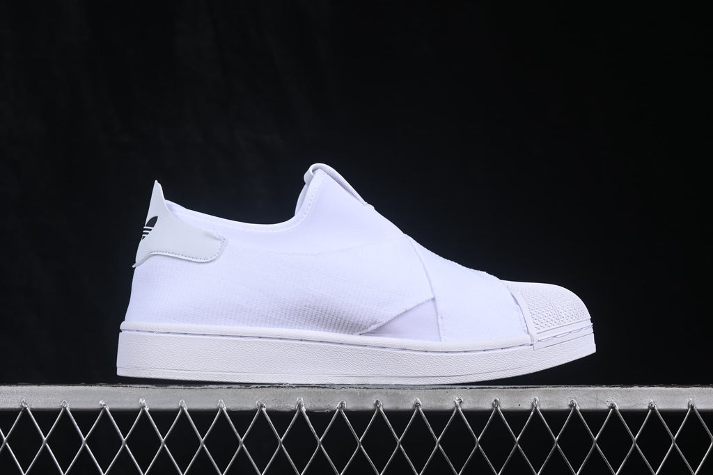 Side profile of the white slip-on sneaker showing the heel tab and layered upper.