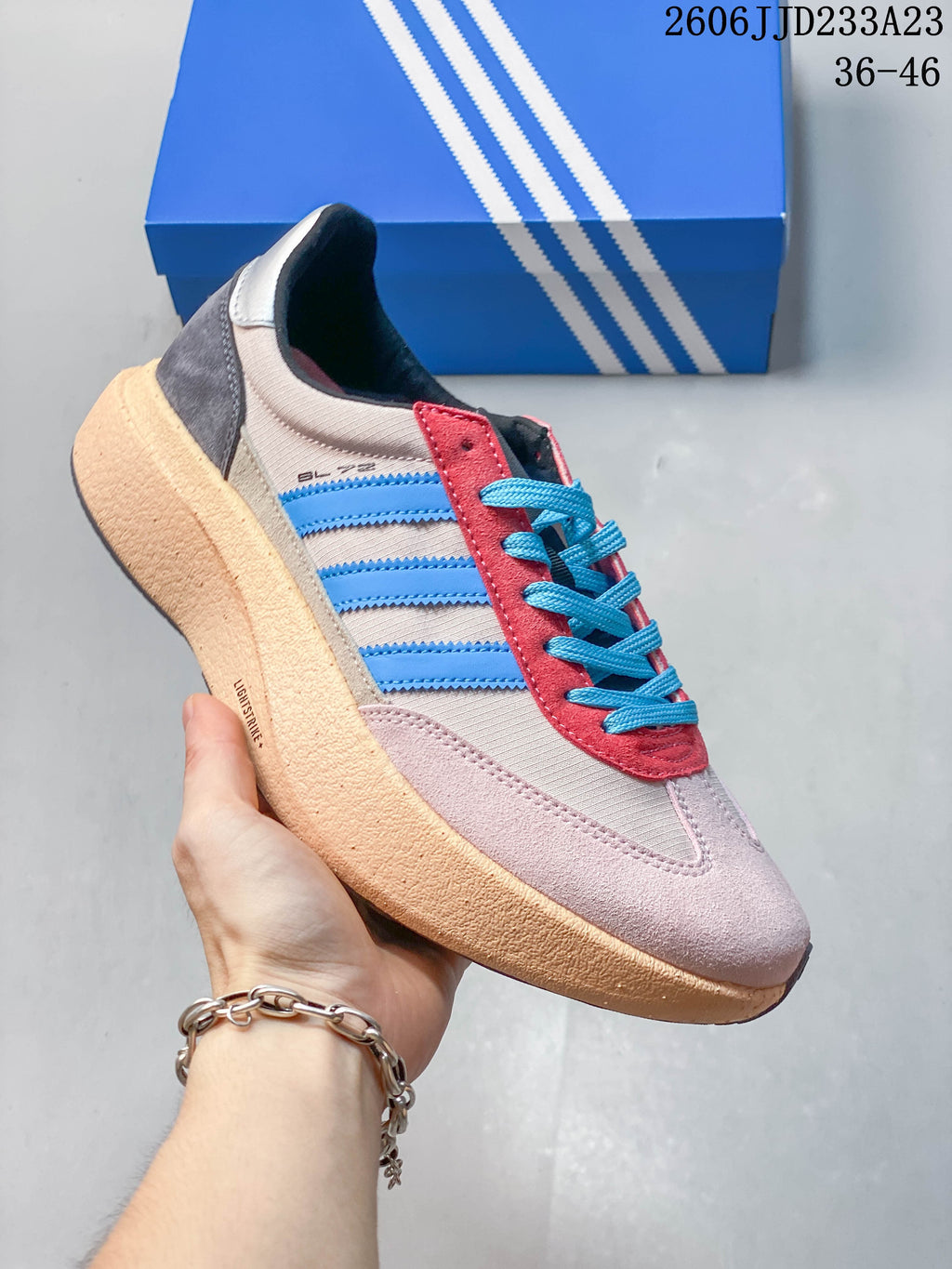Side view of a pale pink adidas Originals SL 72 Pro sneaker with blue stripes, bright blue laces, and red accents.