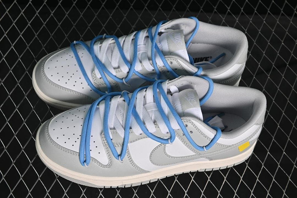 Pair of white and grey low-top sneakers with blue overlay laces