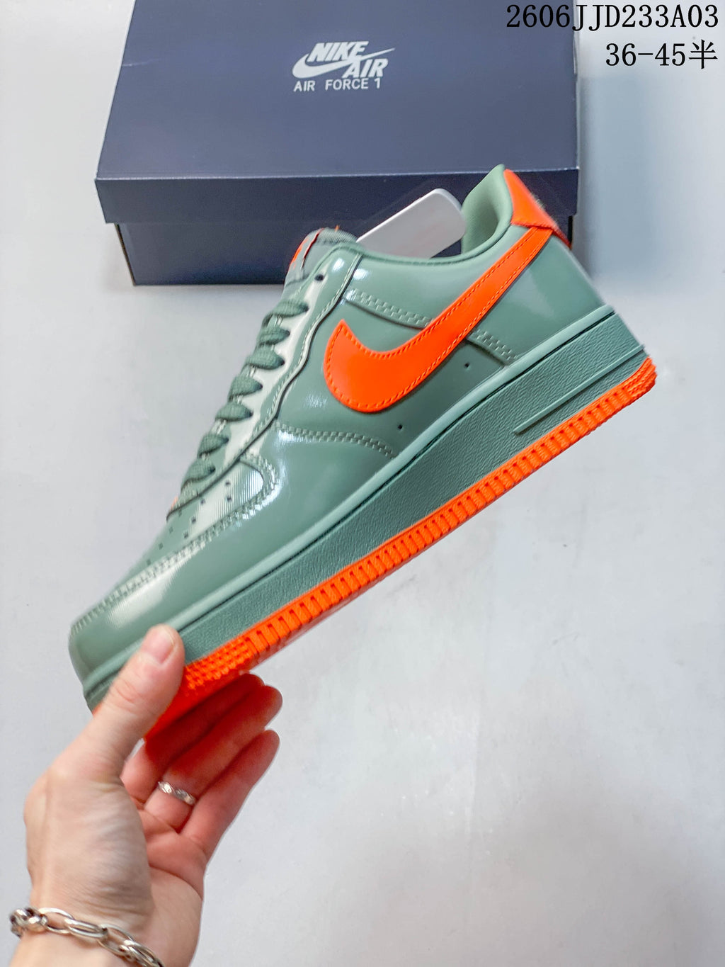 Side profile of a green Air Force 1 ’07 sneaker with an orange Swoosh and outsole
