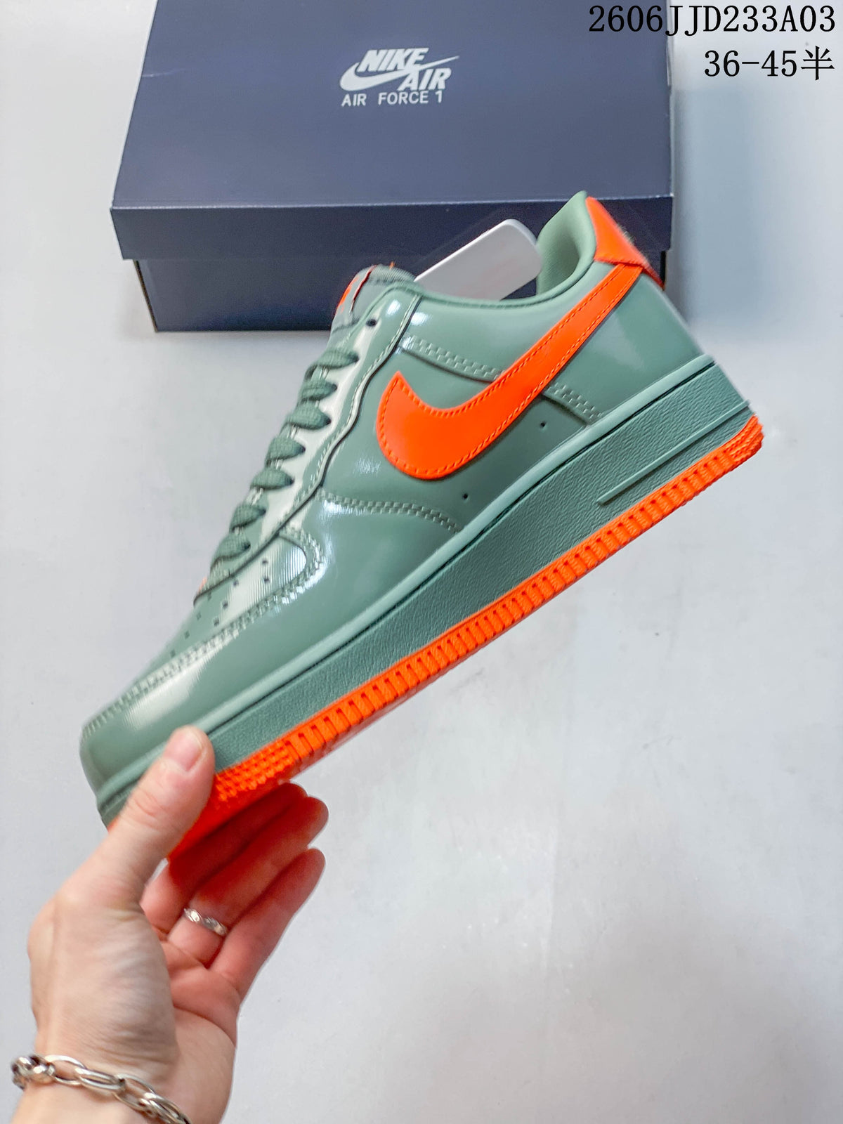 Side profile of a green Air Force 1 ’07 sneaker with an orange Swoosh and outsole