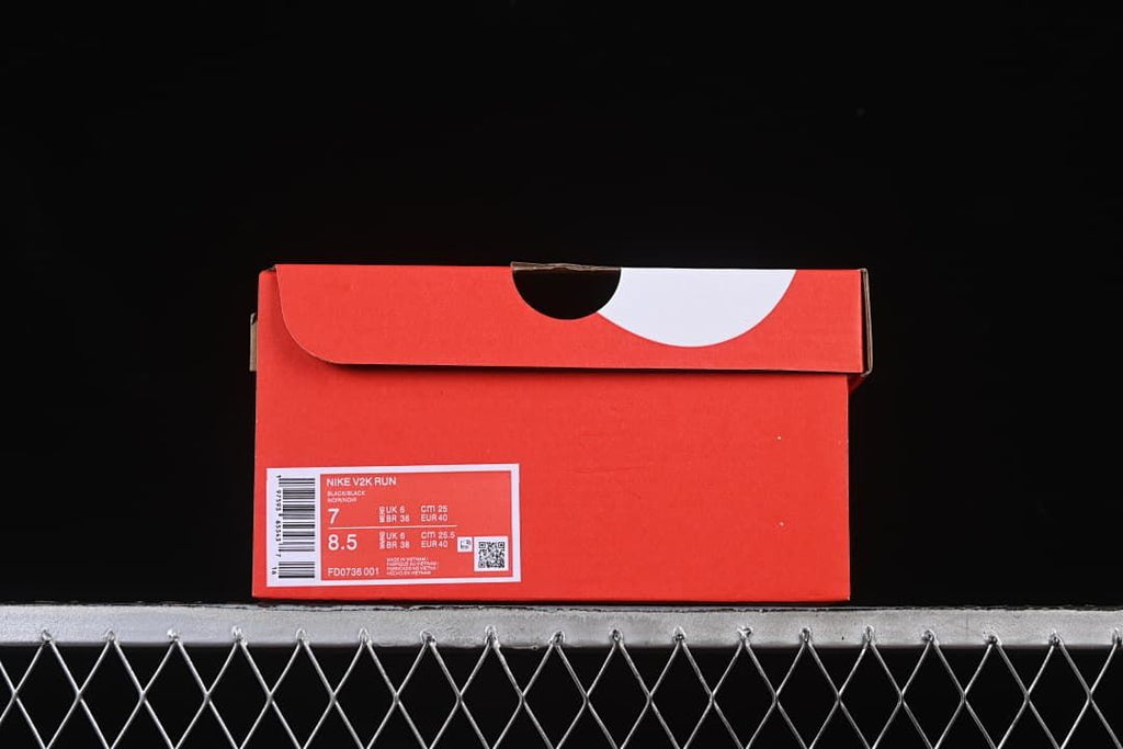 Red shoe box with a product label for Nike V2K Run.