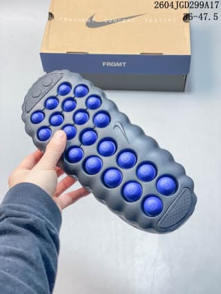 Bottom view of the slide showing multiple raised blue circular outsole nodes.
