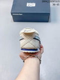 Rear view of the cream and blue Onitsuka Tiger sneaker held in front of its branded box.