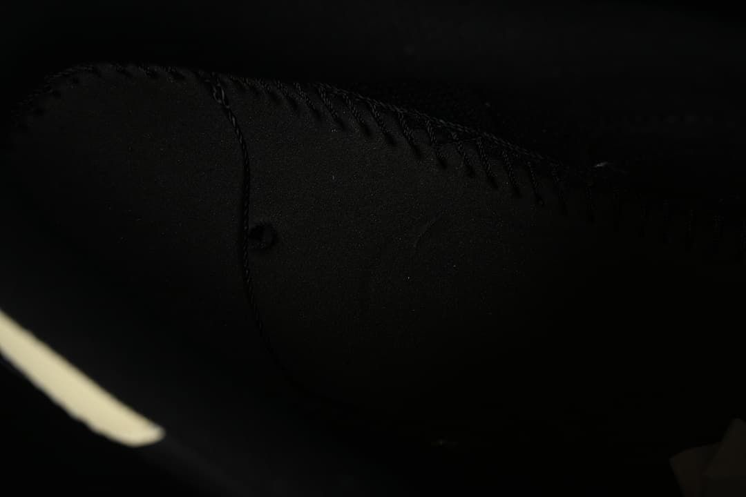 Dark close-up of stitching and interior construction inside the sneaker.